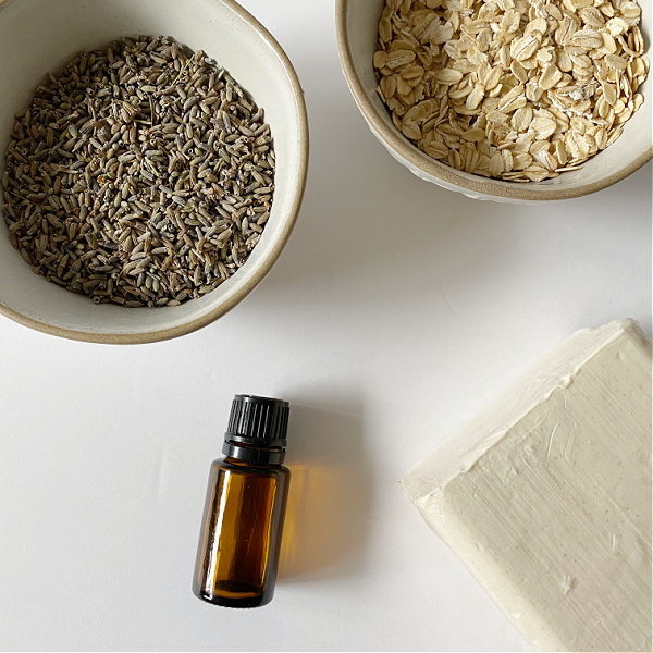 Ingredients needed to make bar soap without lye: oatmeal soap base, dried lavender, oats, and essential oil.
